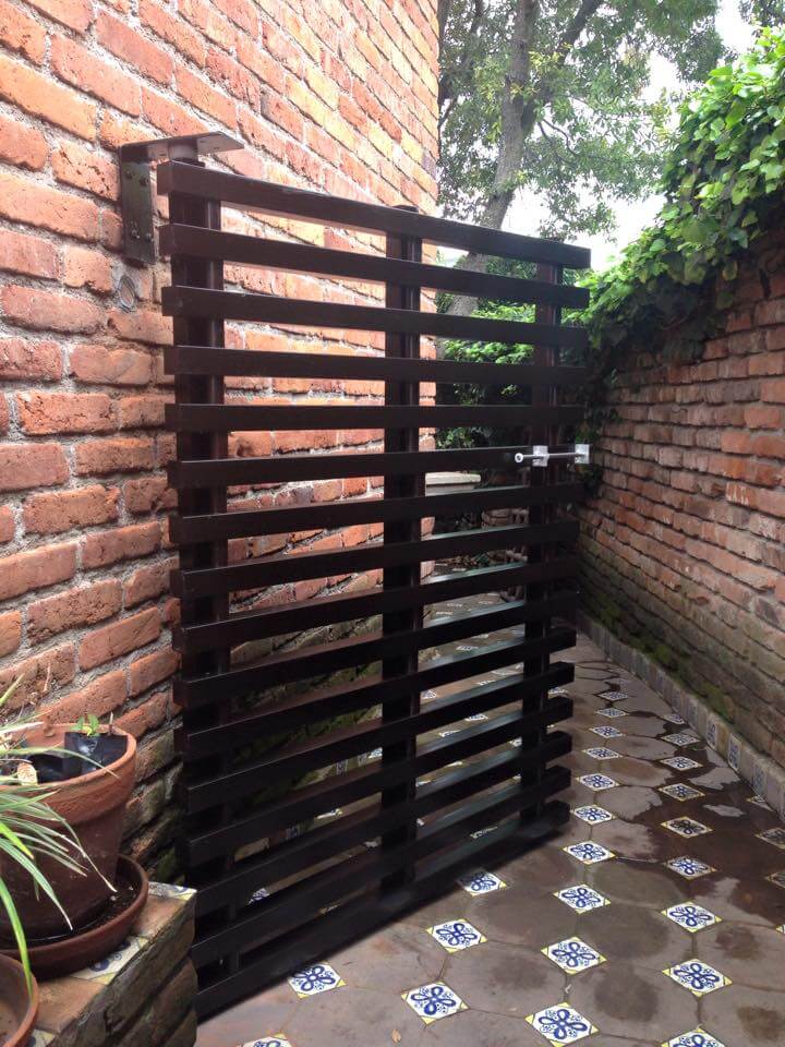 Puerta de celosía horizontal en patio con muro de ladrillo